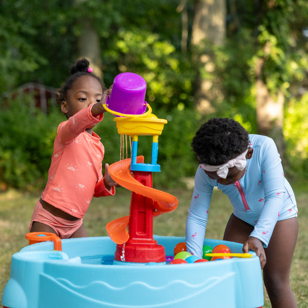 Spiral Slide Water Table™ child pouring water into top of tower