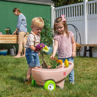 Springtime Wheelbarrow - Rose Pink with kids playing with flowers.