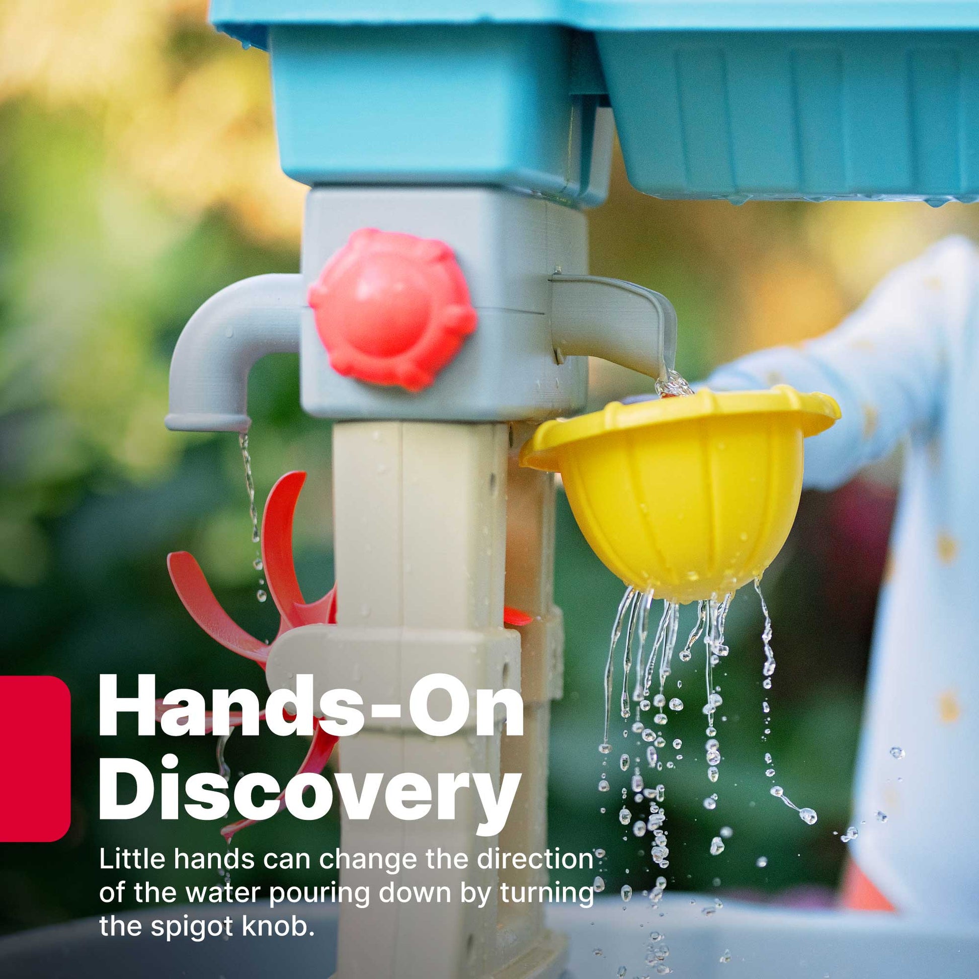 Rain Showers & Flow Water Table™ close-up of spigot knob and water flow feature, water cascading into yellow cup, garden background