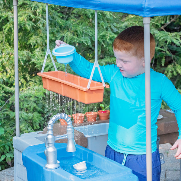Grill & Splash Play Center with Canopy™ child pouring water into hanging rain shower tray