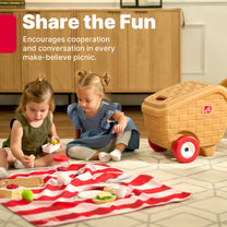 Share the Fun — two girls playing with toy picnic food items on red-and-white checkered blanket on rug; My First Picnic Basket in background