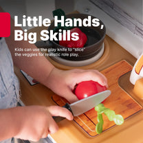 "Little Hands, Big Skills" — close-up of toddler hands using a play knife on the Garden Fresh Kitchen™ cutting board with a tomato; "Kids can use the play knife to 'slice' the veggies for realistic role play"