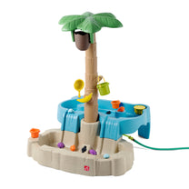 Step2 Tropical Splash Water Park™ — full set on white background: tall palm tree with coconut-shell spout, upper sand-colored rock basin, lower square blue water table basin; accessories include green bucket, yellow sieve, orange cup, banana connector, and hose attachment