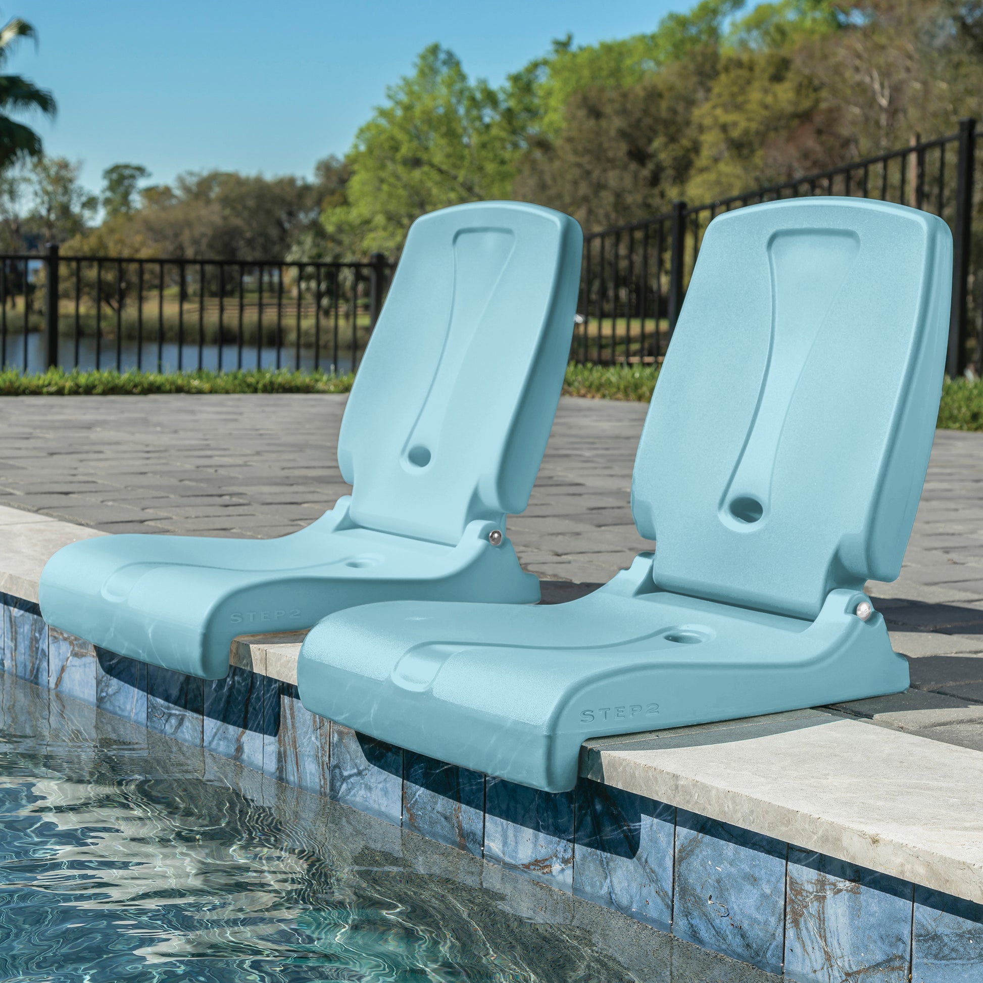 Two Flip Seat™ chairs in teal positioned side by side at a pool edge with backrests upright overlooking the water