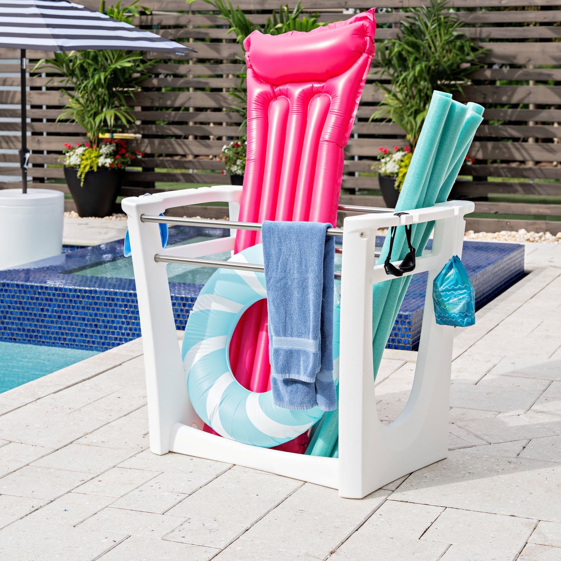 Step2 Vero Pool Side Organizer™ white poolside storage rack holding inflatable raft, pool noodles, ring float, and towels