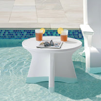 Step2 Vero In Pool Accent Table™ placed in shallow pool water holding two drinks with lemon, sunglasses, and a magazine on the round top; blue mosaic pool tile surrounds; white Vero chair partially visible at right