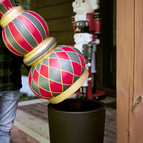 Man placing hand-painted ornament spheres into a dark holiday planter