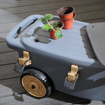 Top-down view of EverTough Garden Hopper on deck — lid open with seedling pots on surface, foam pad slid aside