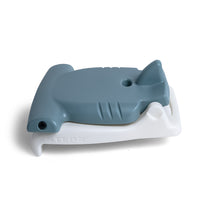 Kids Hammerhead Flip Seat in gray folded flat, front-left angle — hammerhead fin, gill marks, eye, and STEP2 on white base, on white background