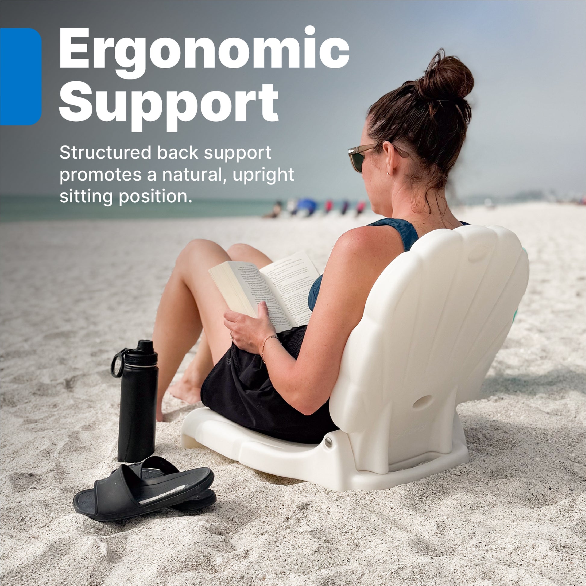 Seashell Flip Seat Ergonomic Support — woman reading a book on beach seated on white seashell flip seat, with water bottle and sandals nearby