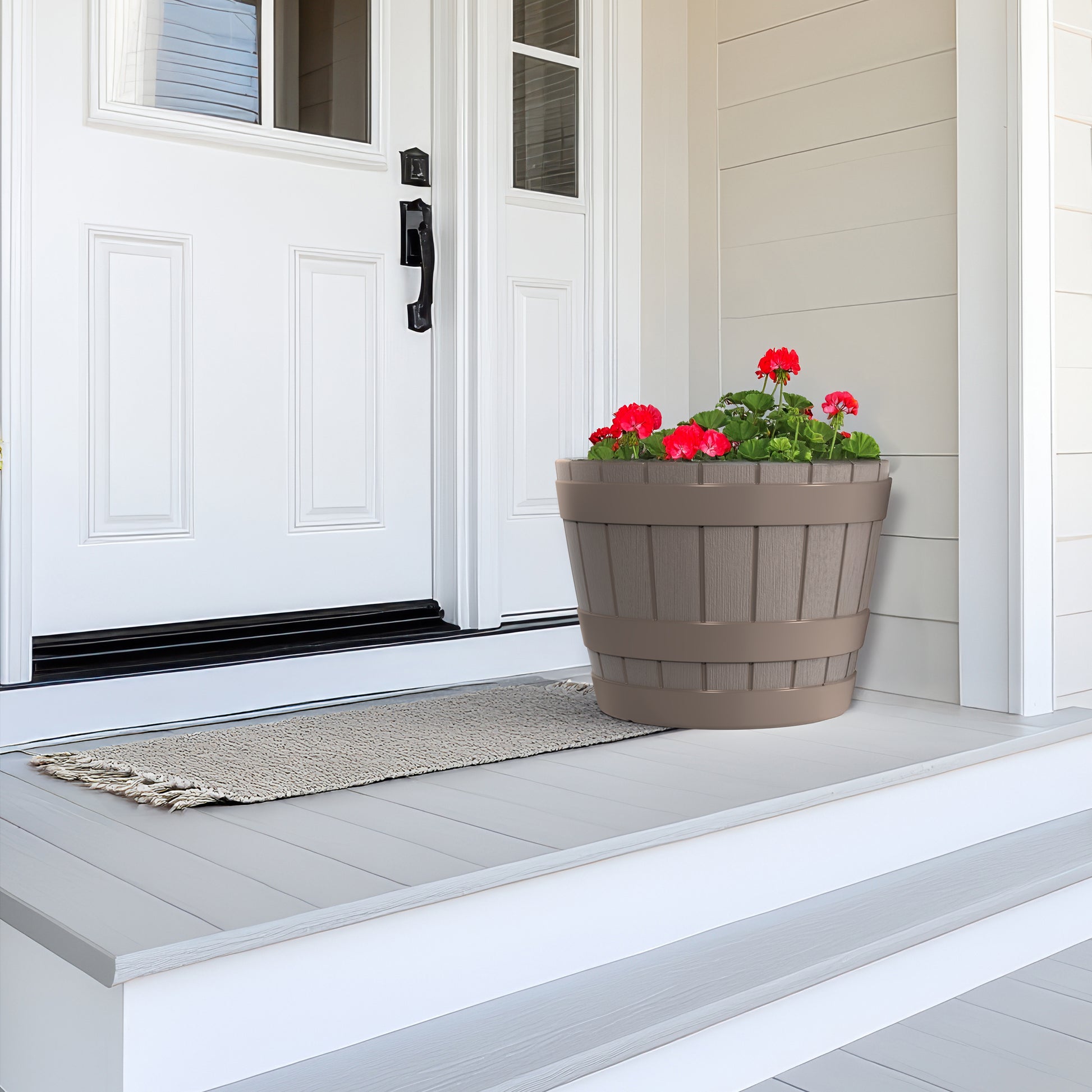 American Oak Planter™ with vibrant red geraniums displayed on front porch steps next to a white door
