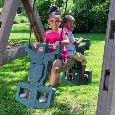 Naturally Playful™ Adventure Lodge Play Center with Glider with 2 children riding the glider