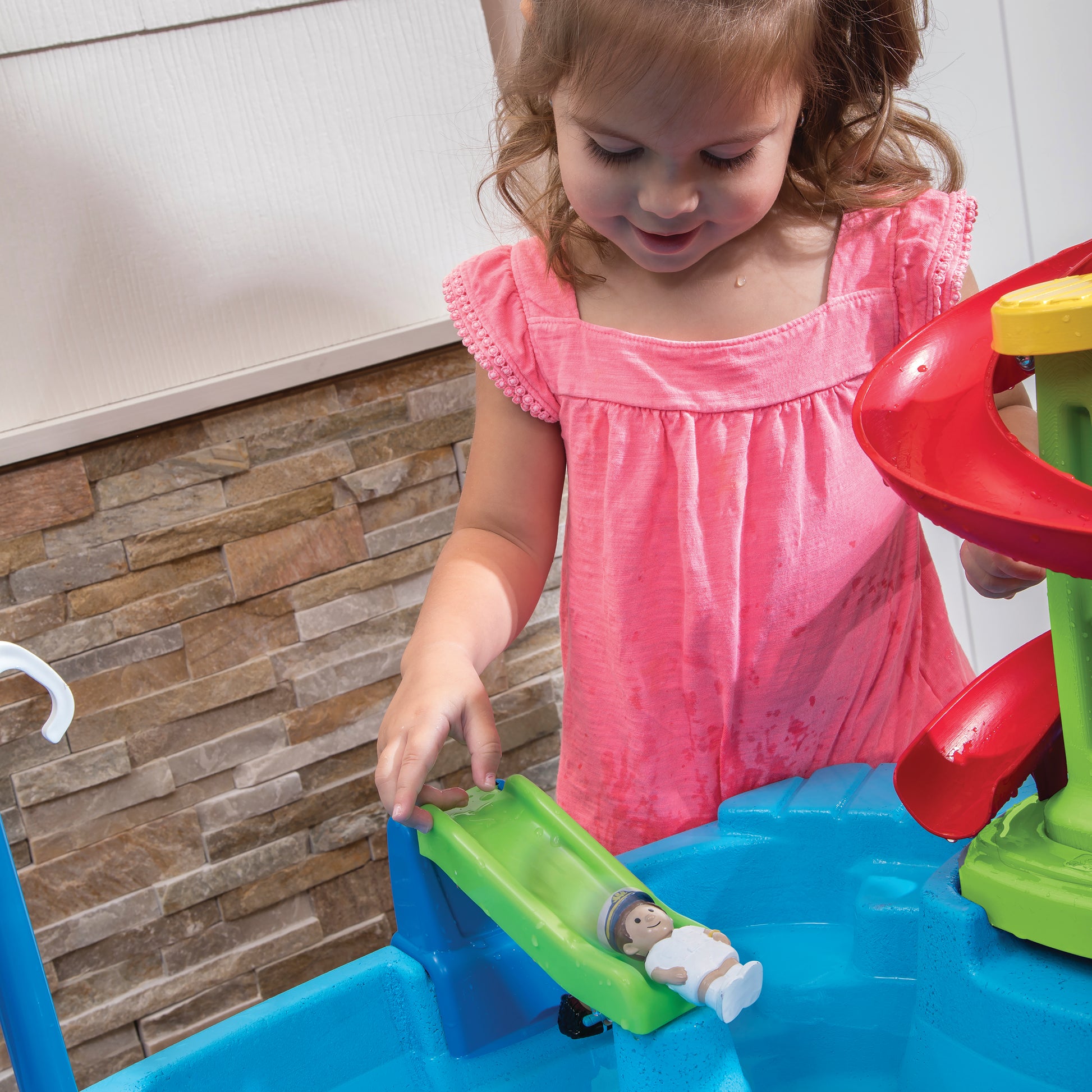 Close-up of girl reaching for green slide with toy captain figure on Fiesta Cruise Water Table