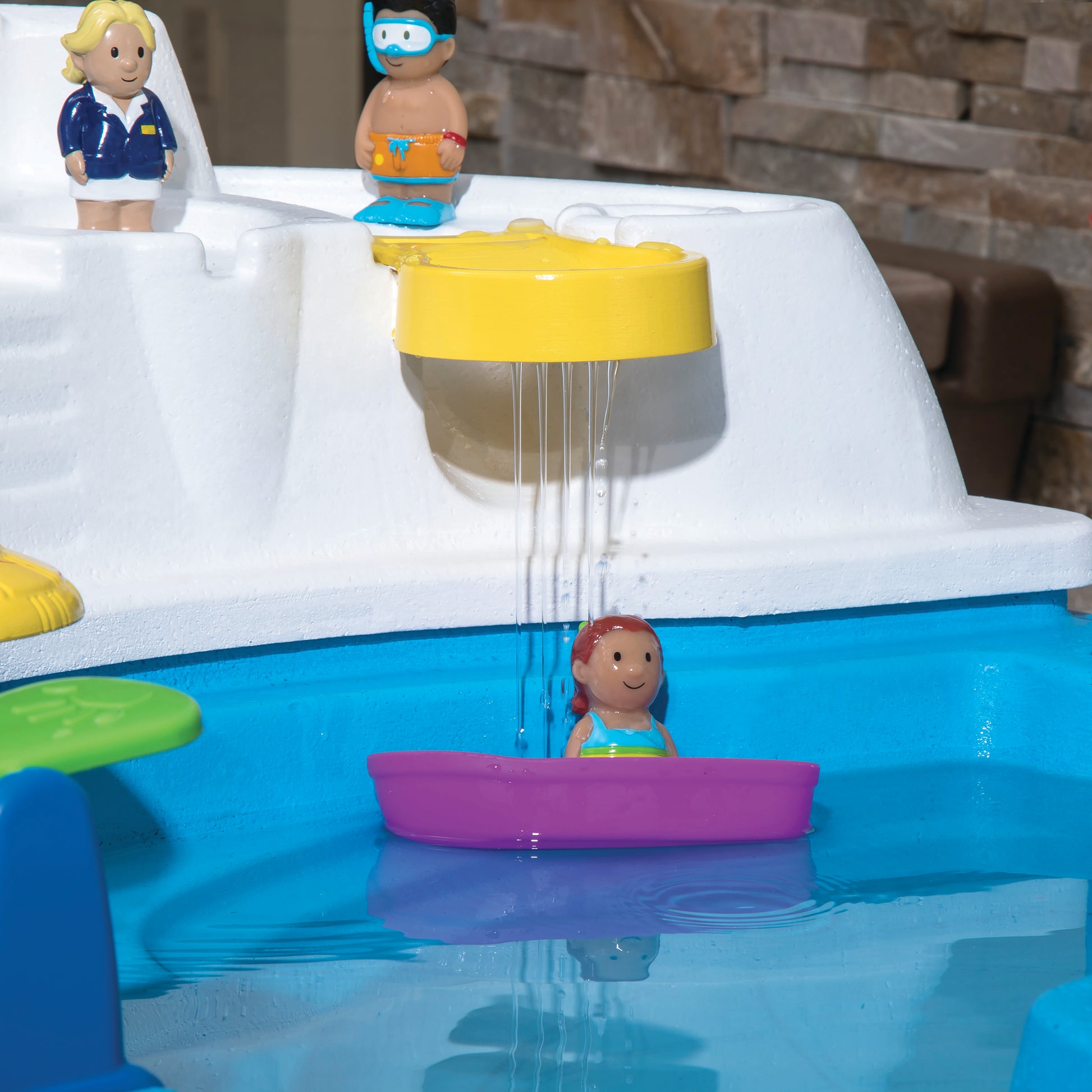 Close-up of Fiesta Cruise Water Table water section with yellow rain shower, purple toy boat with girl figure, and captain and diver figures on cabin deck