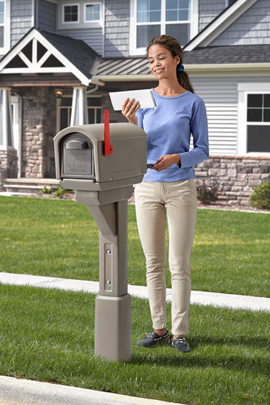 Woman standing next to a mailbox with a red flag in front of a house