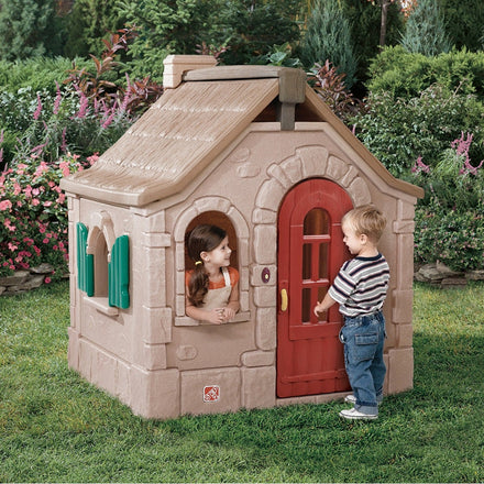Children playing with a playhouse in a garden setting