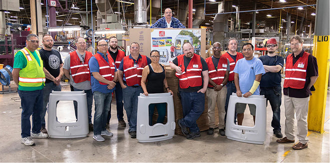 Group of people in a warehouse setting with large gray containers.