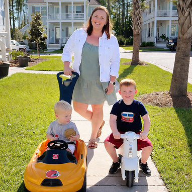 Woman with two children on toy cars in a residential area