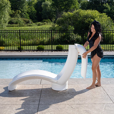 Woman standing next to a white modern lounge chair by a pool