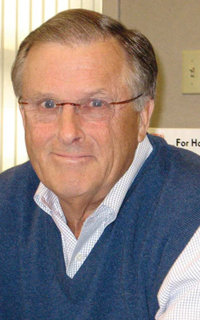 Man wearing glasses and a blue sweater over a white shirt