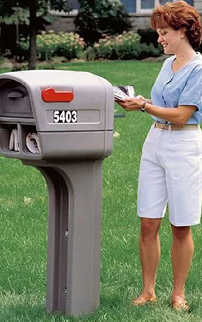 Woman standing next to a mailbox with address '5403' on a grassy lawn.
