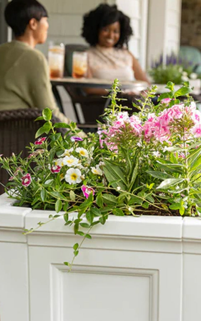 Floral arrangement in a white planter with people in the background