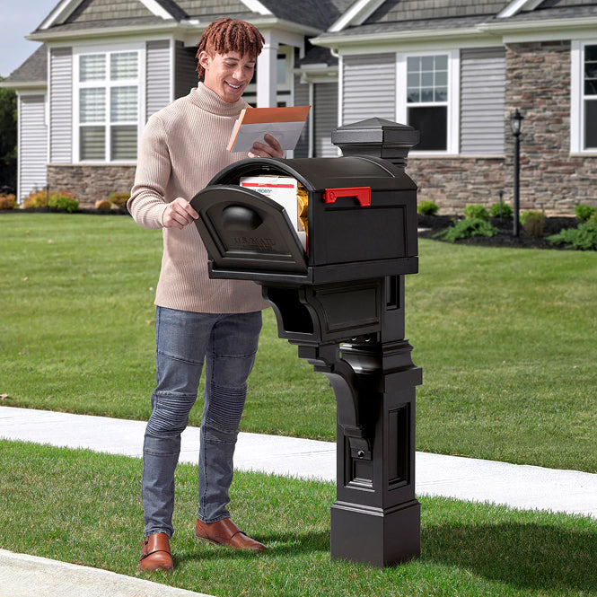 Person opening a black mailbox in front of a house