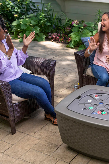 Two women sitting outdoors with a game table in front of them