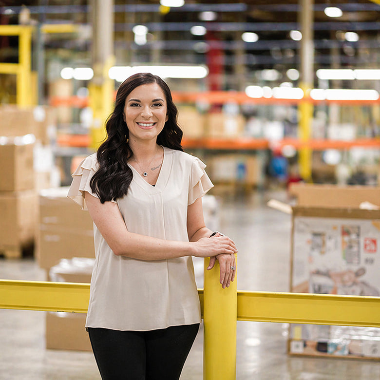 Woman standing in a warehouse with boxes and equipment in the background
