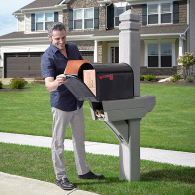 Man checking mail at a black  mailbox with post in front of a suburban home